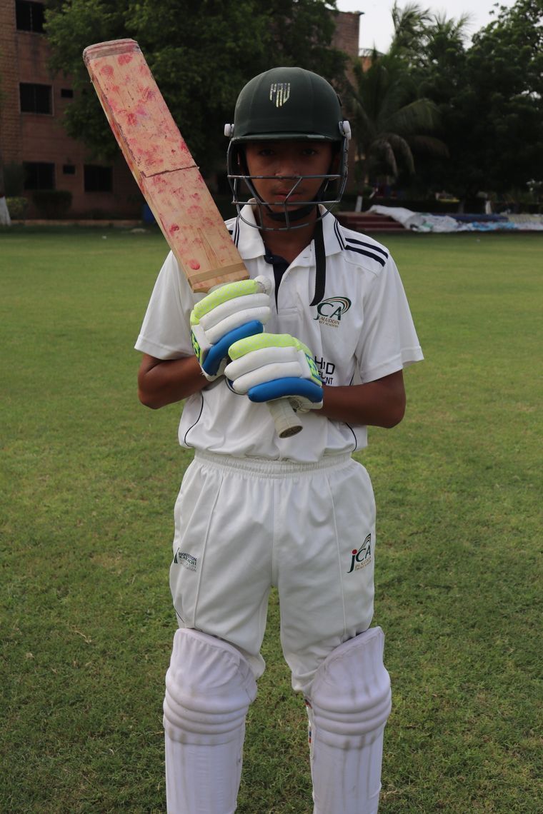 A boy in cricket whites holding his bat
