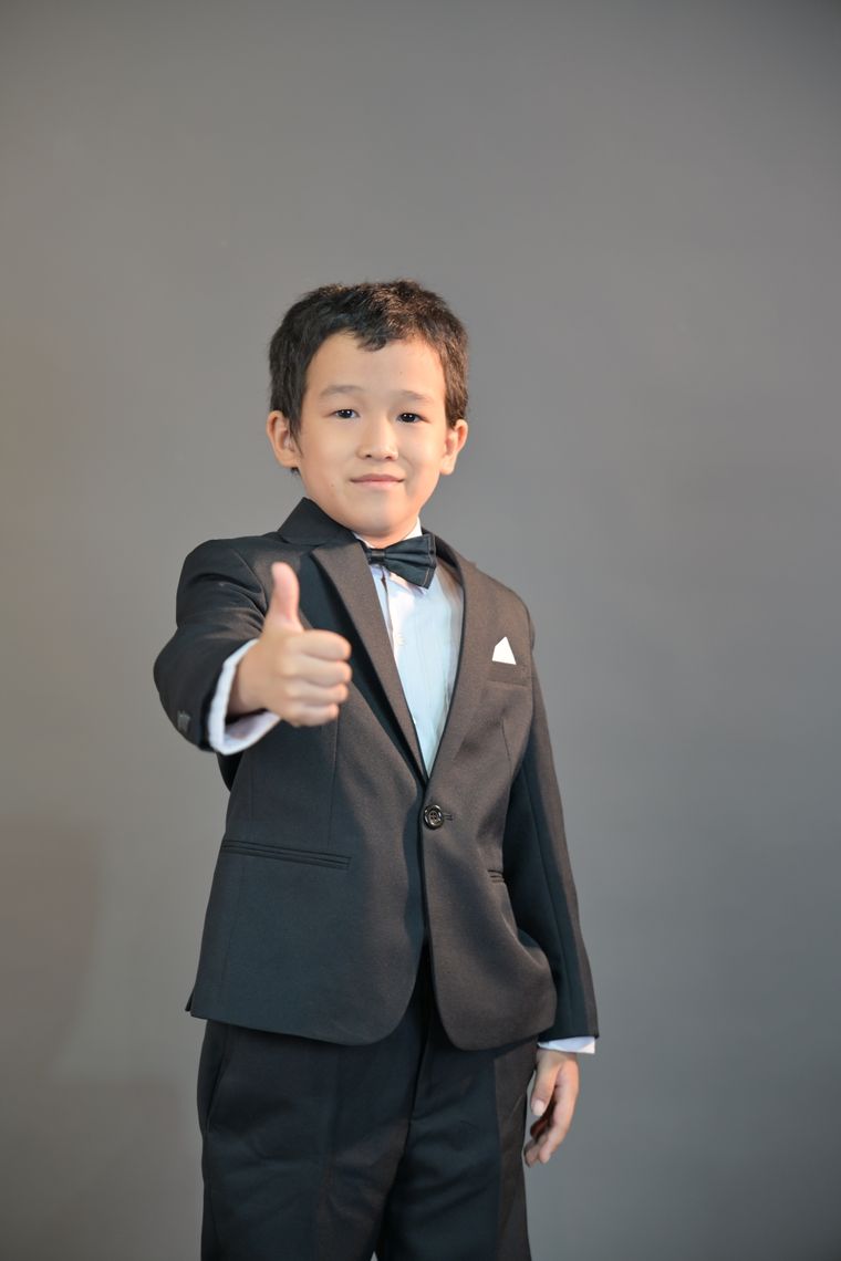 A boy in a suit giving a thumbs-up