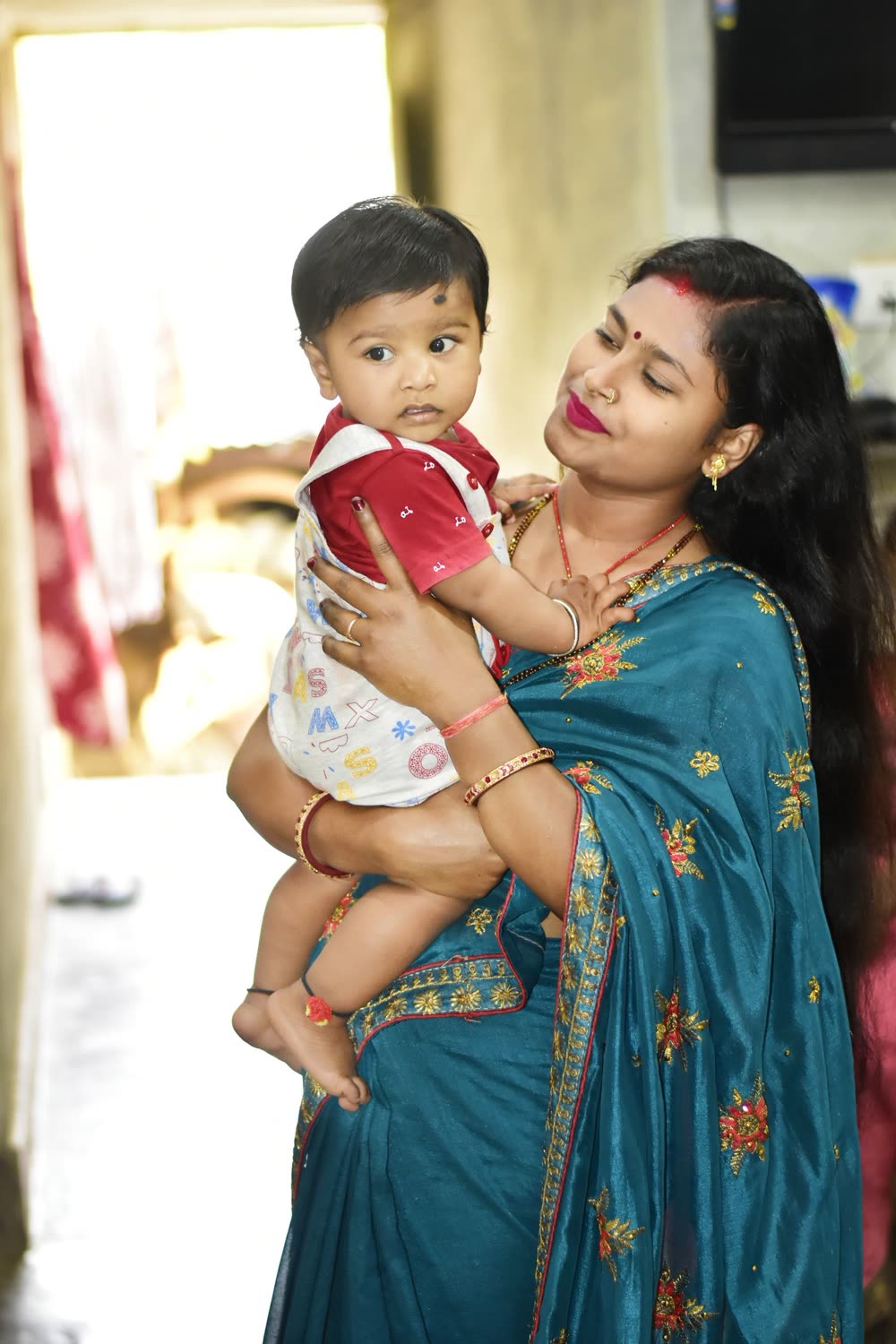A mother in a saree holding her baby close