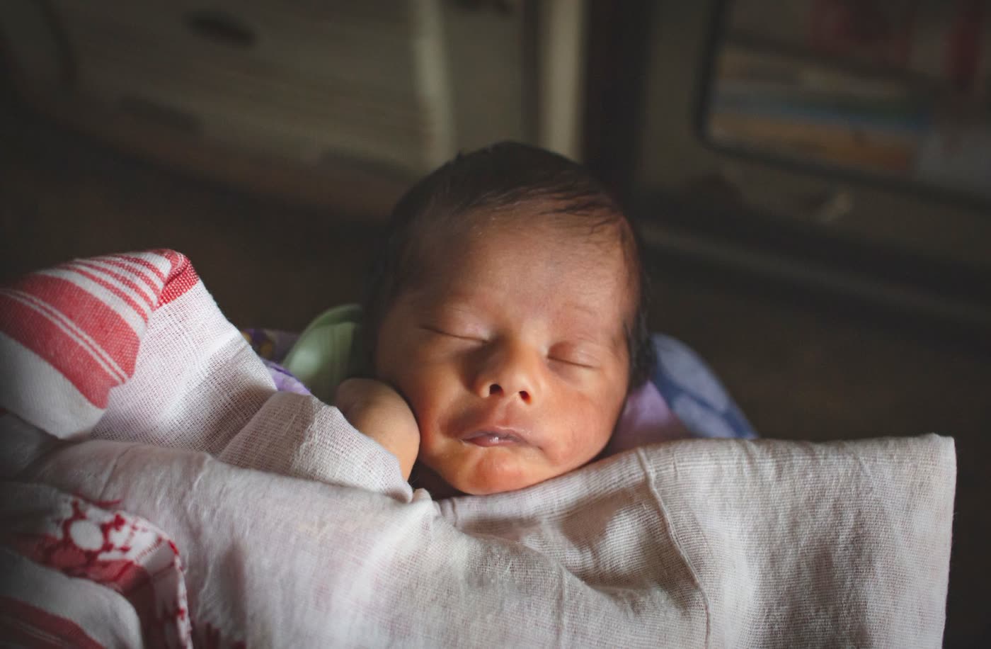 A newborn baby sleeping peacefully, wrapped in a soft cloth