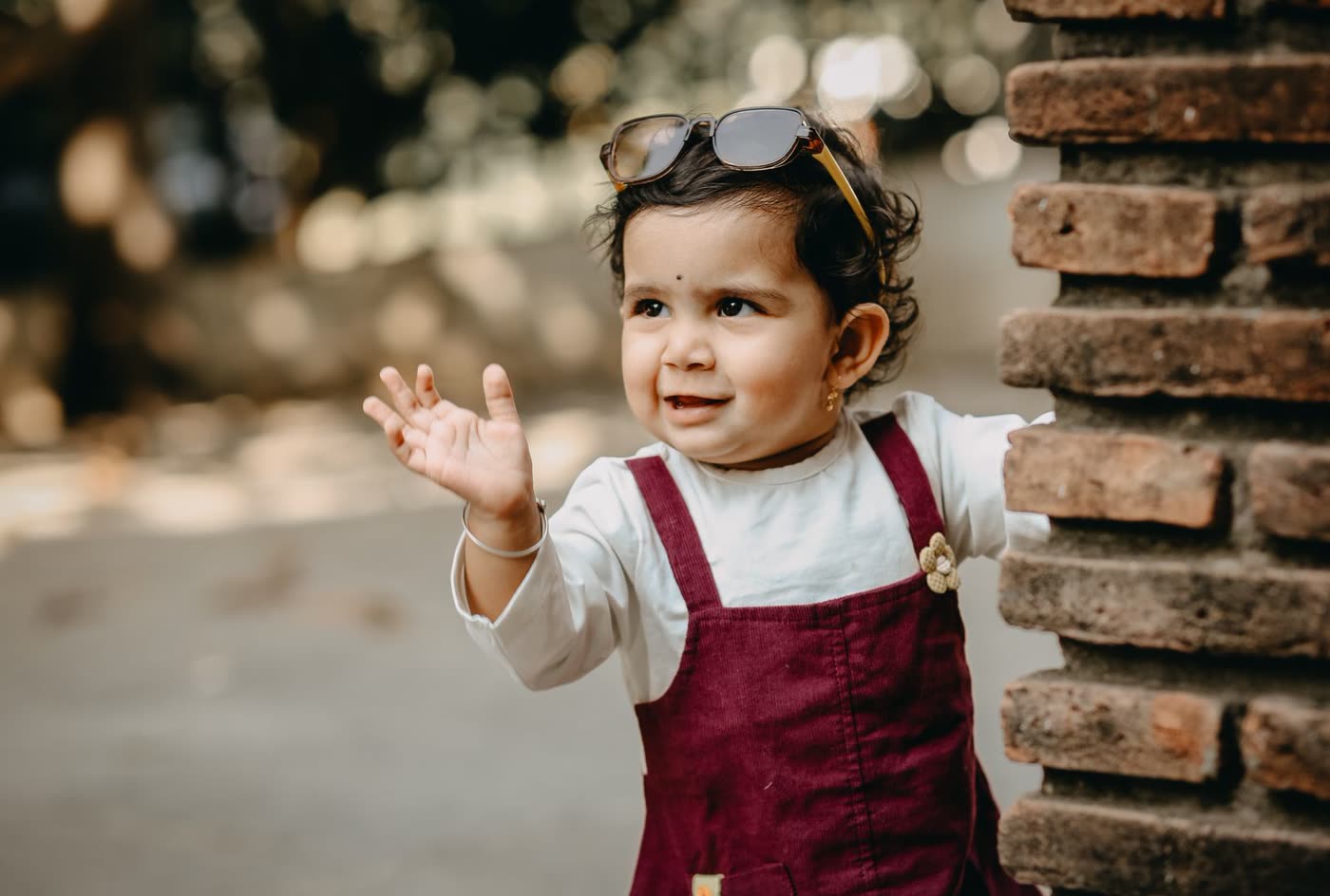A cheerful toddler girl waving outdoors
